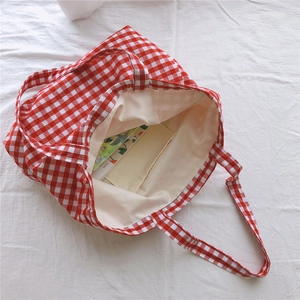 Detail view of red and white gingham tote bag featuring inner pocket and beige lining
