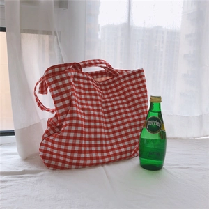 Detail of red and white checkered canvas tote bag with cotton handles in bright setting