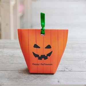 Halloween pumpkin gift bag with green ribbon tie on wooden surface, festive design