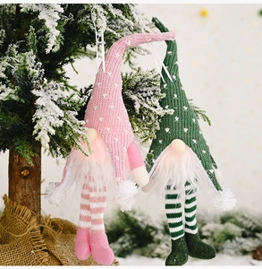 Christmas glowing faceless gnome ornaments in pink and green on snow-dusted tree branches
