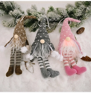 Close-up of three lighted Christmas gnomes with long legs on snow with pine branches