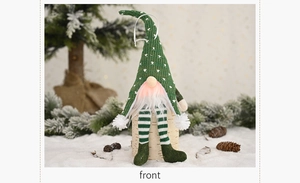 Close-up of a Christmas gnome doll with green knitted hat and white beard in snow setting