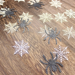 Glittery black spiders and white spider webs on dark wood for Halloween party decor