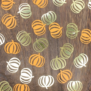 Festive Halloween pumpkin confetti in orange and gold on a dark wood background
