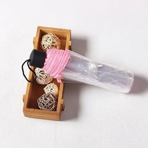 Detail of compact pink mini folding umbrella with black handle in a clear protective case