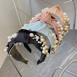 Detail of wide knotted fabric headbands with elegant pearl and bead embellishments