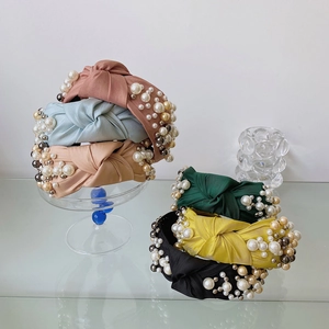 Detail showing knotted wide headbands with pearls in assorted pastel silk colors