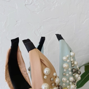 Detailed close-up of knot headbands with pearls and blue satin fabric texture