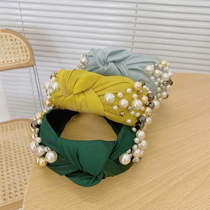 Detail of satin fabric headbands with knot design and assorted white pearl embellishments