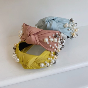 Detailed view of knot headbands with satin fabric and multi-sized pearl embellishments