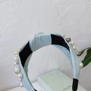 Detail of light blue satin knotted headband featuring white pearls and gold bead accents