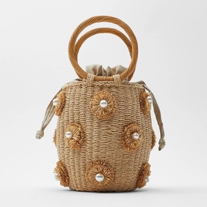 Macro detail of hand-woven straw bag featuring decorative 3D flowers and white pearls