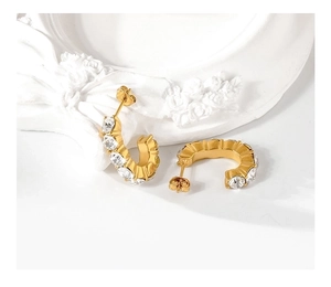 Detail view of gold C-shaped earrings with clear cubic zirconia in a prong setting