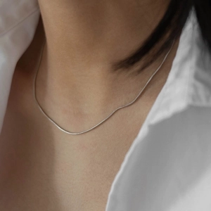 Elegant silver snake chain necklace in stainless steel worn on a collarbone