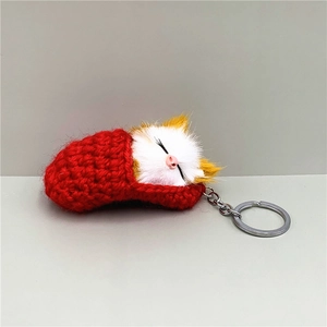 Detail of cute sleeping cat keychain with plush head, red knit body and silver metal ring