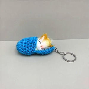 Macro shot of blue knitted sleeping bag keychain with a realistic orange and white plush cat