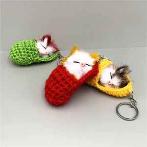 Cute sleeping cat keychain plush hanging in red, green, and yellow knitted slippers