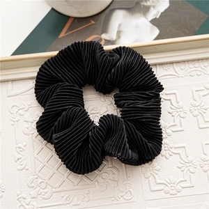 Detailed view of black pleated velvet scrunchie featuring elegant textured fabric ripples