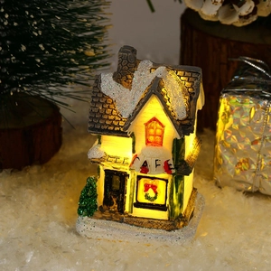 Close-up of a lit resin Christmas cafe house with snow details and warm LED glow