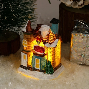 Macro shot of resin Christmas village house with LED lights and snow-covered roof