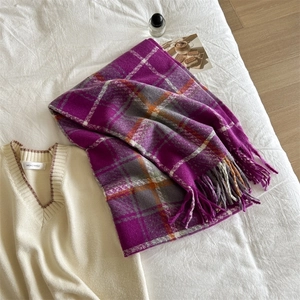 Detailed texture of purple plaid scarf with tassels on cozy white bedding