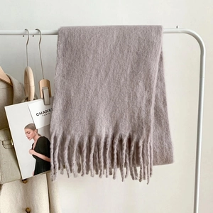 Close-up of taupe cashmere-like scarf with thick fringe tassels on a wooden hanger