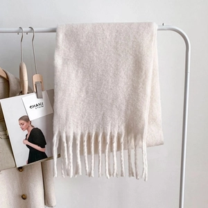 Detail of white knit scarf with thick fringe tassels and soft mohair texture