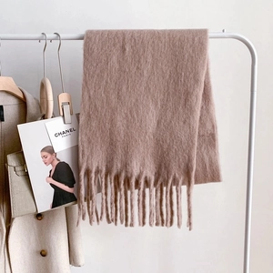Detail of soft khaki faux cashmere scarf with fringe tassels on a minimalist hanger