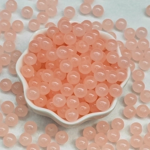 Pink translucent glass jade-like beads in a white bowl for DIY jewelry making