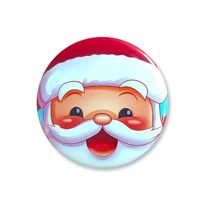 Close-up of a round tinplate Christmas badge featuring a colorful cartoon Santa Claus design