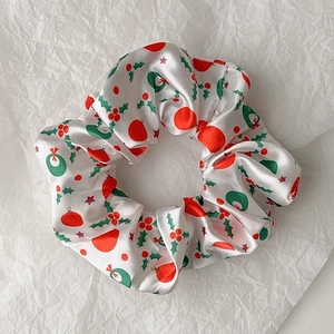 Detail of Christmas scrunchie with holly leaves and berry patterns on white satin
