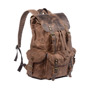 Detail view of vintage brown waxed canvas backpack with leather straps and buckles