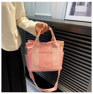 Pink canvas tote bag featuring matching top handles and an adjustable shoulder strap detail