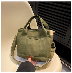 Detail of army green canvas tote bag with adjustable shoulder strap and small front pocket