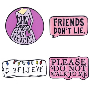 Detailed view of four enamel pins with feminist slogans on a white background