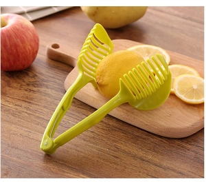 Close-up of green plastic fruit slicer tool cutting a lemon on a wooden board