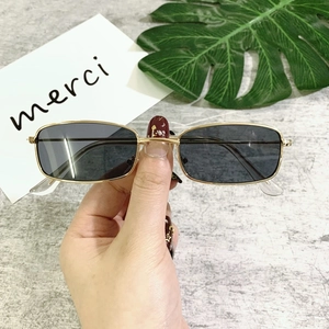 Detail view of small rectangular sunglasses with gold metal frames and dark lenses
