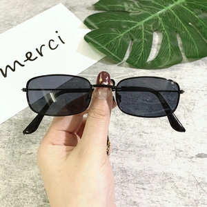Detail of small rectangular sunglasses with slim black metal frame and dark lenses