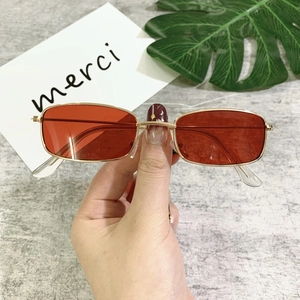 Detail of vintage gold metal rectangle sunglasses with transparent red lenses and slim arms