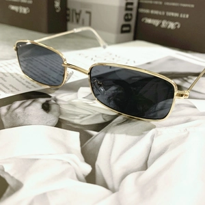 Detail of rectangular gold metal frame sunglasses with dark lenses on a magazine