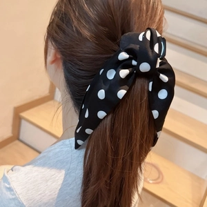 Polka dot fabric bow hair clip worn on a ponytail for an elegant hairstyle