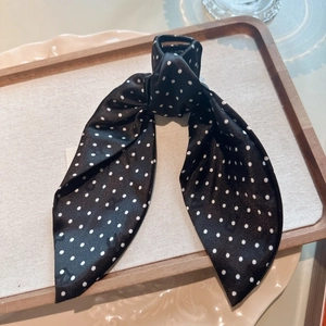 Detailed shot of black polka dot fabric bow hair claw on a rustic wooden tray