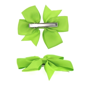 Detail of green grosgrain ribbon bow hair clips with metal duckbill clips on white base