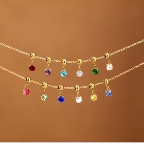Detail view of mini 18K gold zodiac birthstone pendants with colorful zircon crystals