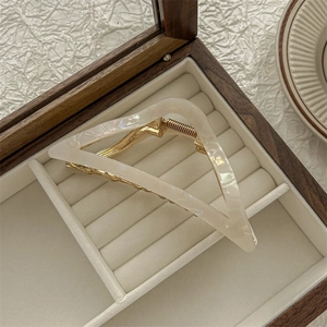 Detailed view of white shell texture triangle hair claw clip in a wooden jewelry box