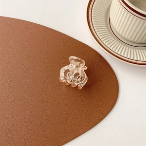 Detailed shot of a mini amber acrylic hair claw clip on a brown textured leather surface