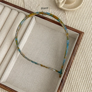 Detail of tortoise shell acetate headband with blue and yellow patterns in a wooden tray
