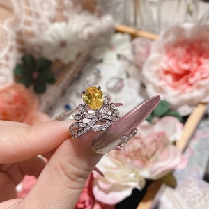 Macro detail of silver crown ring featuring large yellow oval gemstone and sparkling zircons