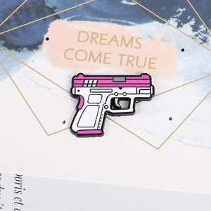 Macro shot of a pink cartoon pistol enamel pin on a decorative dreams come true card