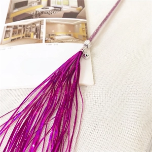 Detail of purple tinsel cat wand featuring a silver bell and shiny tassel threads